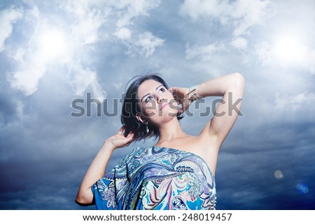 Beautiful young woman on a background of sky and clouds expressing purity and freedom