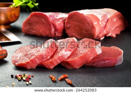 Fresh and raw meat. Sirloin medallions steaks in a row ready to cook. Background black blackboard