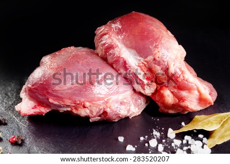 Fresh and raw meat. Cheeks, red pork ready to cook on the grill or barbecue. Black slate background