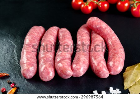 Raw and fresh meat. Fresh sausages and chicken meat ready to cook. Black slate background. Butchers\' meat.