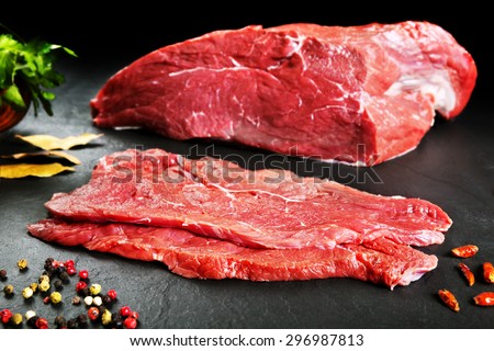 Fresh and raw meat. Steaks in a row ready to cook. Black slate background. Butchers\' meat.