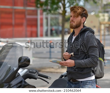 Middle bearded aged man on scooter with map searching his way
