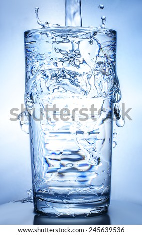 fresh cool water pouring into glass, natural background