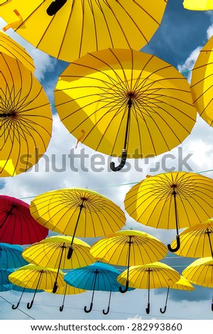 colorful yellow, red and blue  umbrellas under the beautiful  cloudy sky. summer background