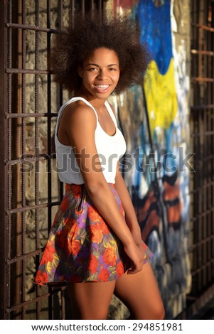 young happy and  pretty afro woman standing and laughing  near old wall