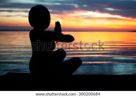 young woman practicing yoga on the ocean beach . natural summer background with beautiful sunset