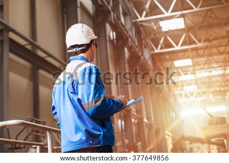 builder in hard hat looking at an industrial interior. Metal smelting plant