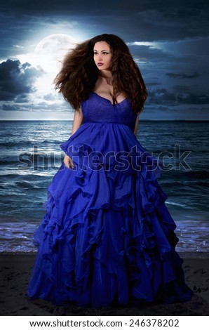 Beautiful Mysterious woman in long blue dress at ocean beach. Fantasy woman. Water Goddess. Book cover.