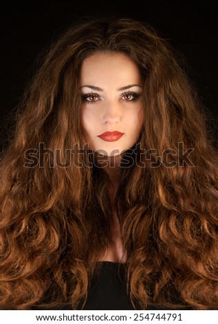 Beautiful mysterious young brunette woman with amazing curly hair. Hair products model. Fantasy woman portrait. Book cover.