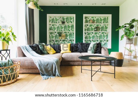 Modern and cozy living room with corduroy sofa, coffee table, plants and big window to the garden. Bright and sunny family space.