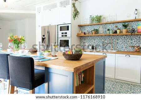 Stylish and sunny kitchen interior with accessories, wooden table and plants. Design space.