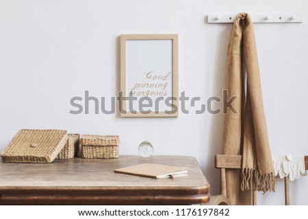 Stylish interior design of kitchen space with small table with mock up frame, straw box and notebook . Minimalistic interior, white walls.