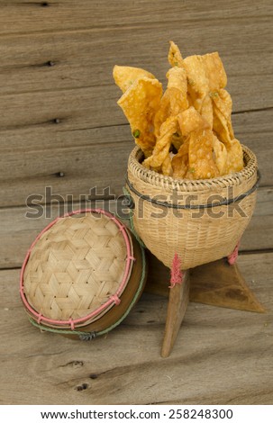 Cheese snacks in bamboo container isolated on wooden table
