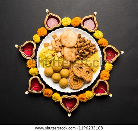 Diwali Rangoli or design made using Indian snacks/sweet and diya or lamp and flowers