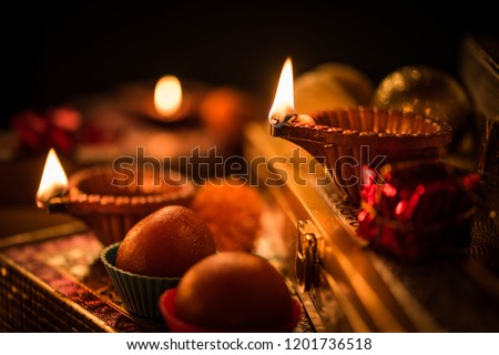 Diwali diya or lighting in the night with gifts, flowers over moody background. Selective focus