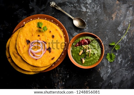 Makki di roti with sarson ka saag, popular punjabi main course recipe in winters made using corn breads mustard leaves curry. served over moody background. selective focus