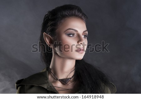 beautiful elf in a cape on a gray background