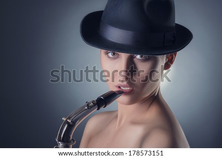 woman with saxophone in hand on gray background
