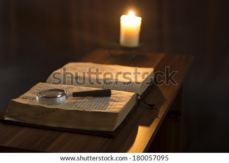 Book and candle on the table on a dark background