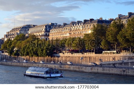 PARIS, FRANCE, OCTOBER 10, 2013 - Excursion boat floats on the Seine river; View  of Paris at sunset