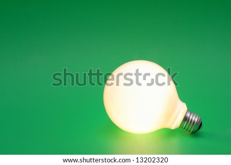 A lit up light bulb on a green background.