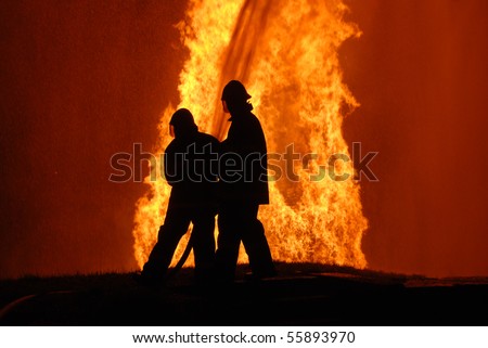 two firemen battling against raging fire, NOTE: top left corner particles are from fire and water spray, not camera noise
