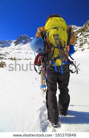 Climber carry backpack and gear on snow covered mountain