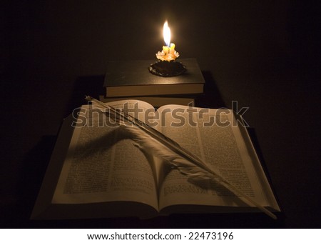 Still life from Bible, books, and feather is lighted up fire  candles.