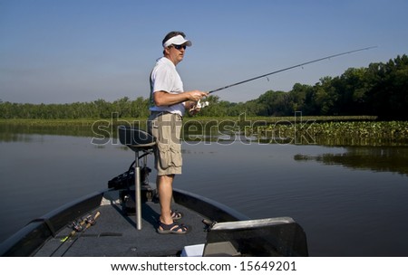 Man fishing in a river off the end of his bass boat.