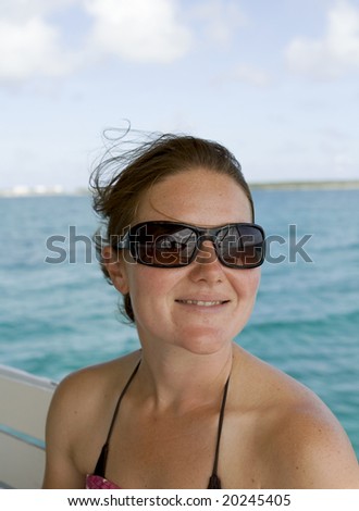Attractive female in bikini smiling with green tropical water in the background.