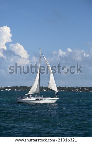 Small sailboat sailing through tropical water.