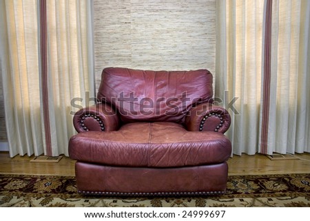 Comfortable leather couch sitting in a room between two windows.