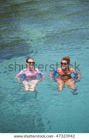 Two young women floating in clear tropical water.