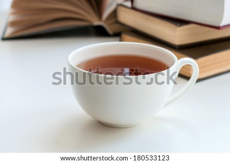 Cup of black tea and some books to read lying on the white table