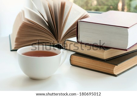 Cup of black tea and some books to read lying on the white table