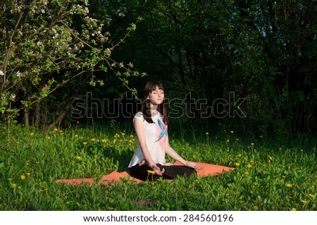 Young woman doing yoga on natural background. Spring garden