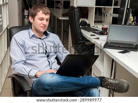 Young handsome man with computer in the office. Thinking over task in programming
