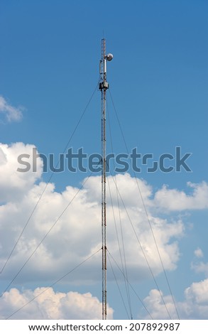 Mobile communications antenna. Cellular telephone antenna GSM against the blue sky and clouds.