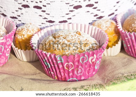 Mini cupcakes in colorful wrapper on a napkin of burlap. Picture taken at the spring fair under the open sky on a sunny day. Close-up. Shallow DOF