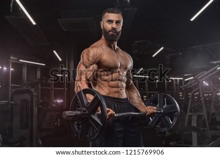 handsome man with big muscles trains in the gym, exercises