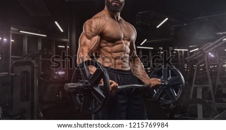 handsome man with big muscles trains in the gym, exercises