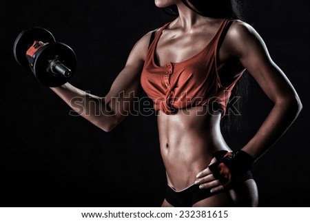 beautiful woman on a dark background is engaged in fitness