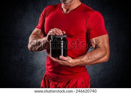 beautiful young athletic man holding a jar of sports nutrition