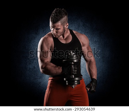 Handsome power athletic man with dumbbell confidently looking forward
