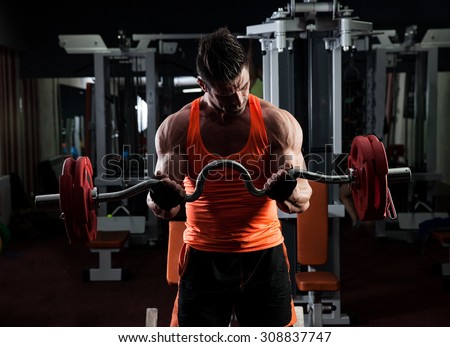 Young adult bodybuilder doing weight lifting in gym.