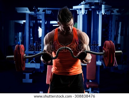 Young adult bodybuilder doing weight lifting in gym.
