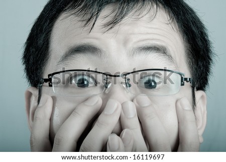 A asian business man shows a surprised expression with his hands covering his mouth in cold tone.