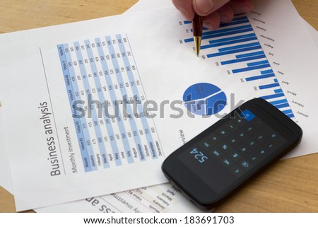 senior businessman holding a pen, analyzing blue charts with calculator