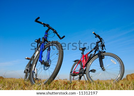 two mountain bicycles stand in the field