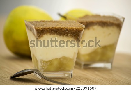 Two apple crumble desserts served on a wooden table and apples in the background.